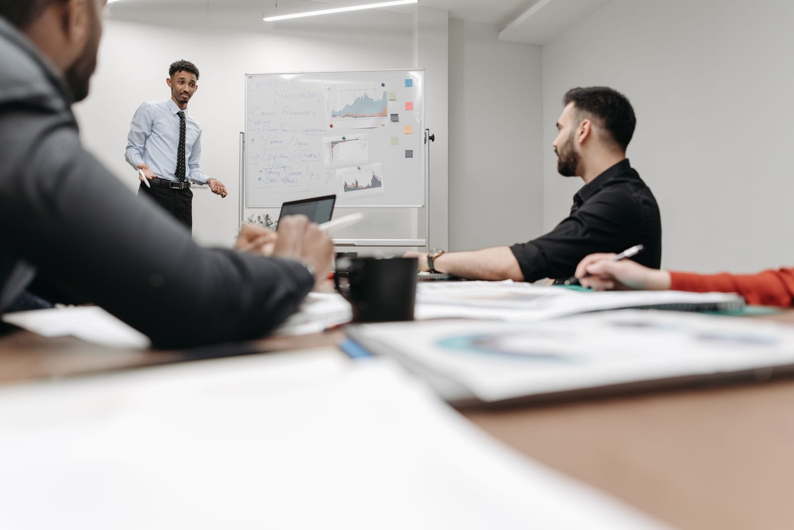 A presenter reviewing marketing charts on a whiteboard with a team in a meeting room