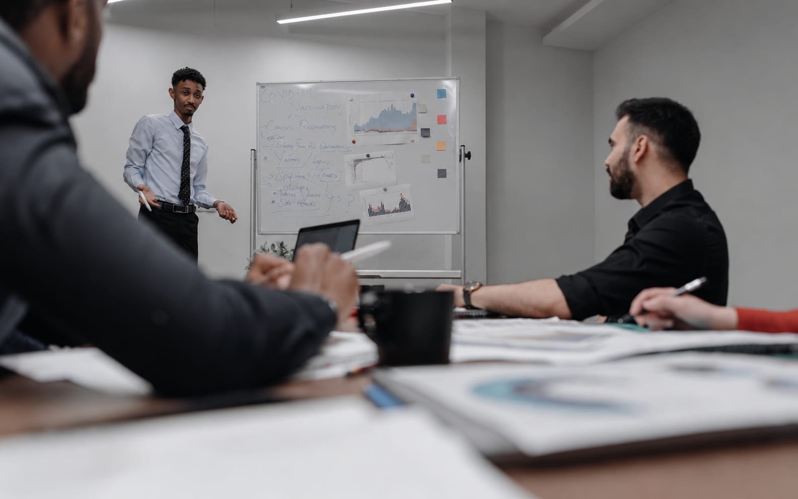 A presenter discussing results with a team around a meeting table
