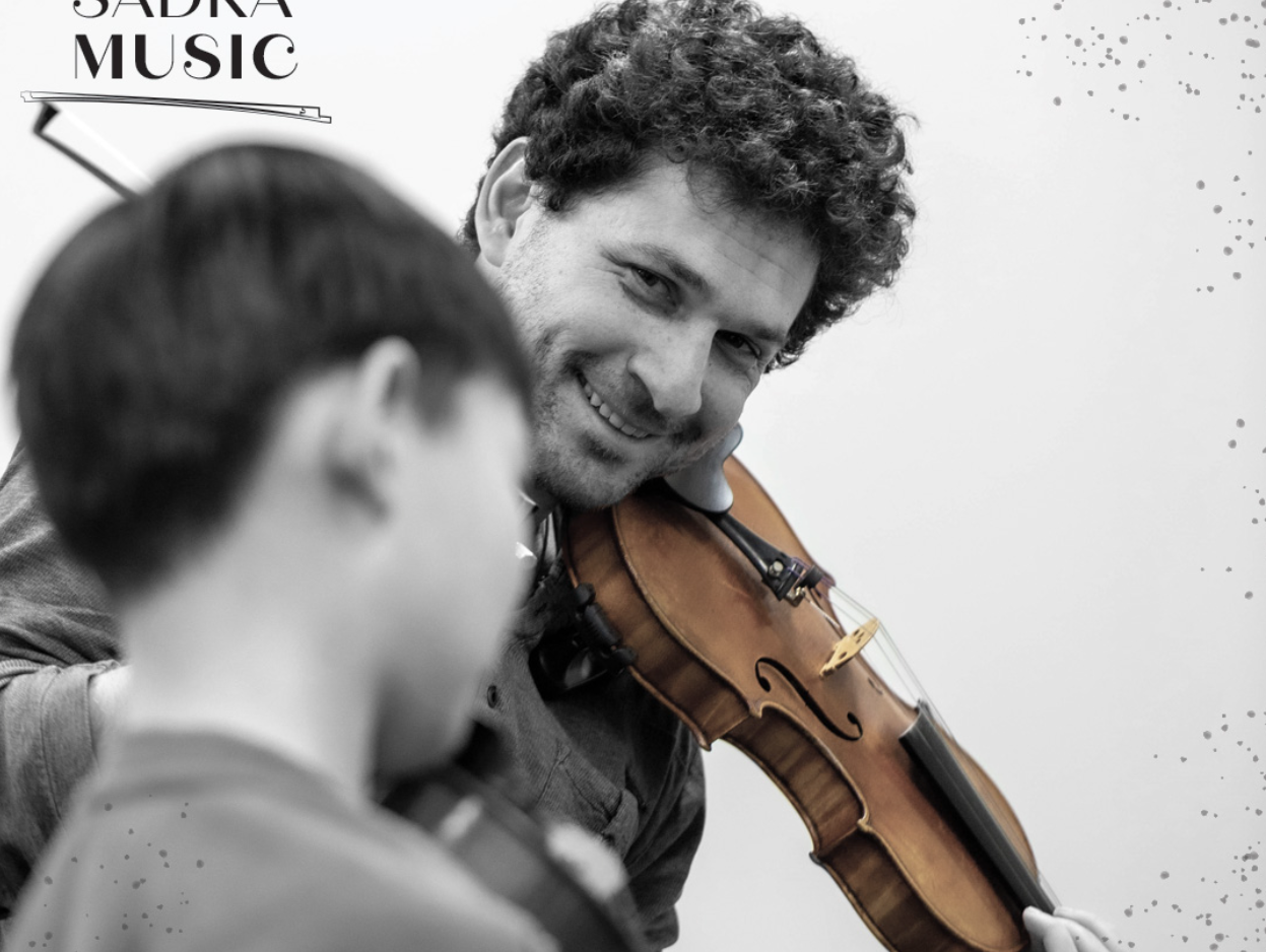 Mark Sadka smiling at a young violin student during a lesson, branded with the Sadka Music mark